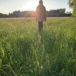Frau steht barfuß in der Natur und genießt die Sonne – Erdung und Verbundenheit mit der Erde
